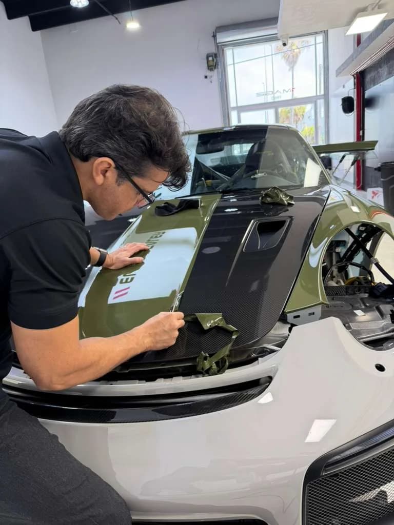 Technician wrapping the carbon hood of an exotic green over carbon