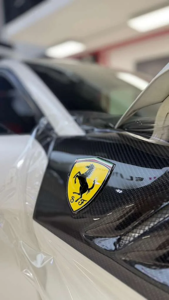 Paint protection film laid over a carbon Ferrari fender badge