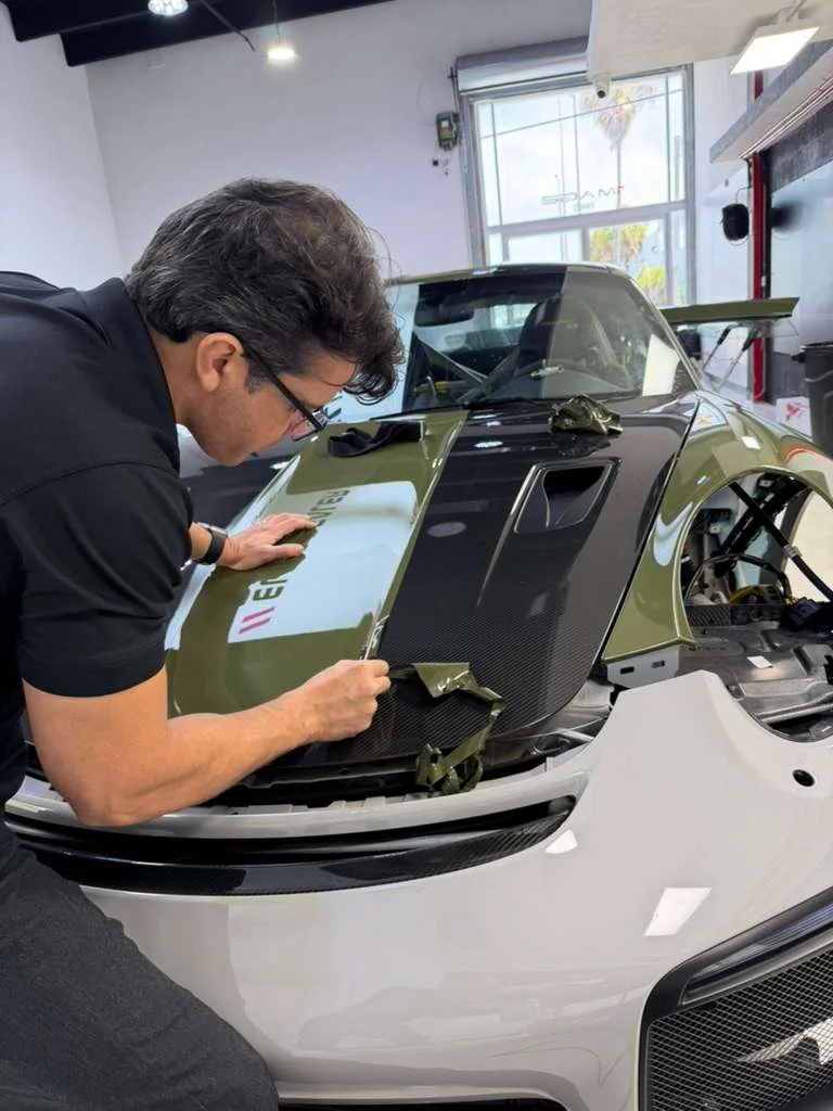 Technician wrapping the carbon hood of an exotic green over carbon